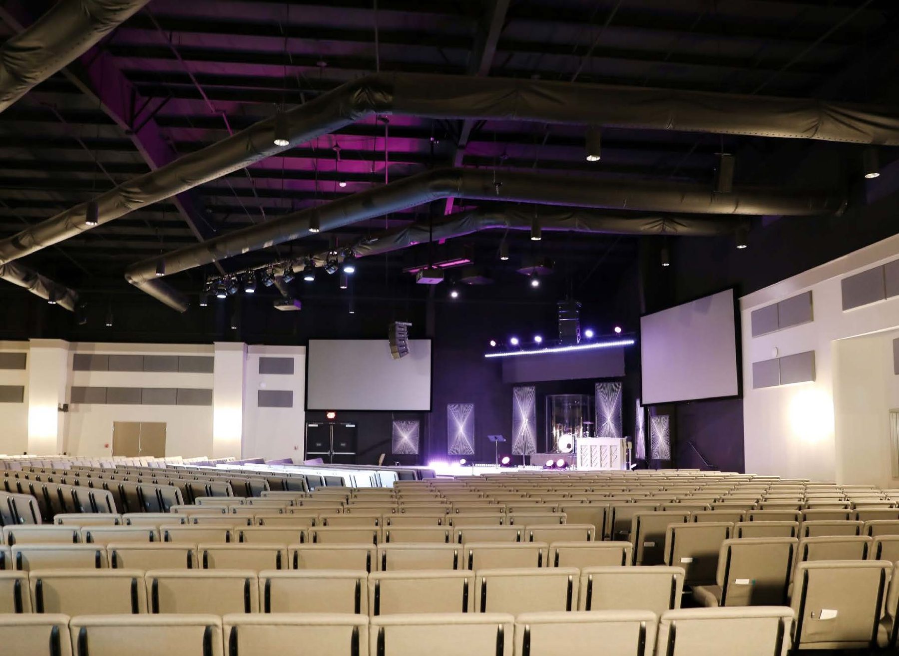 Darkened worship auditorium with tiered seating and stage lighting