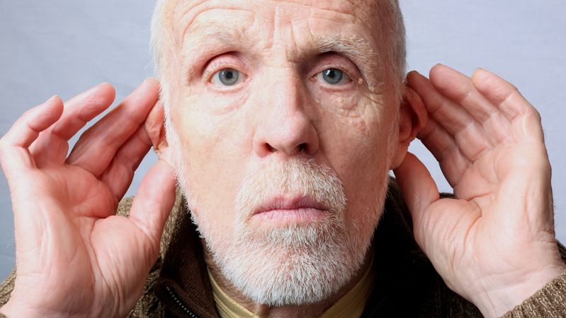 An elderly man is depicted placing his hands behind his ears, signaling a need to hear better. His expression suggests curiosity or attentiveness, creating a connection with the viewer.