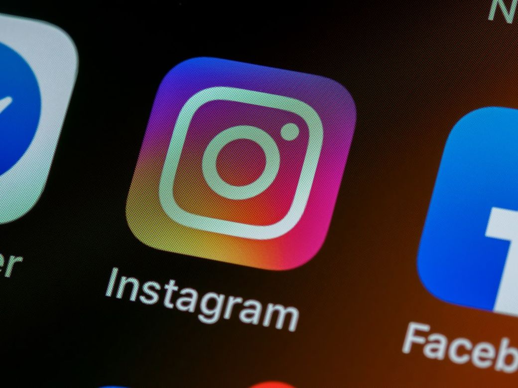 The image depicts a close-up view of a smartphone screen featuring the application icons for Instagram and Facebook. The Instagram icon is prominently displayed, showcasing its signature camera logo against a gradient background. — Credit: Photo by Brett Jordan on Unsplash