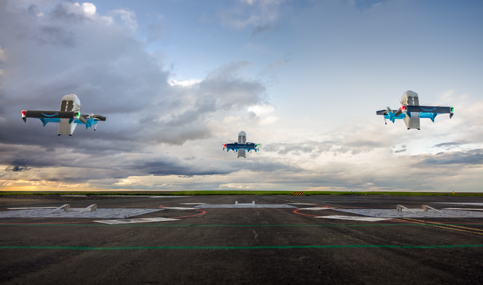 The image depicts three drones flying over an airstrip under a dramatic sky. The drones are equipped with bright lights and a futuristic design, suggesting advanced technology and innovation in aerial vehicles.