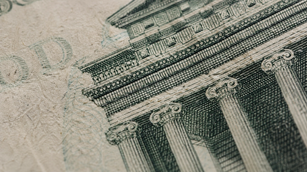 The image features a close-up view of architectural details from a banknote, showcasing intricate designs of columns and a façade. It highlights the craftsmanship involved in currency design.
