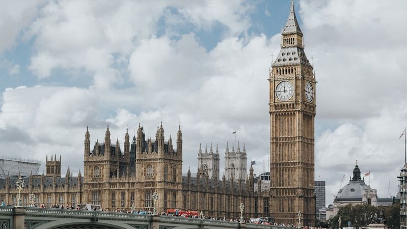 The image showcases the iconic Big Ben clock tower along with the Houses of Parliament in London. It captures a vibrant scene under a partly cloudy sky, emphasizing the historic architecture of the city.