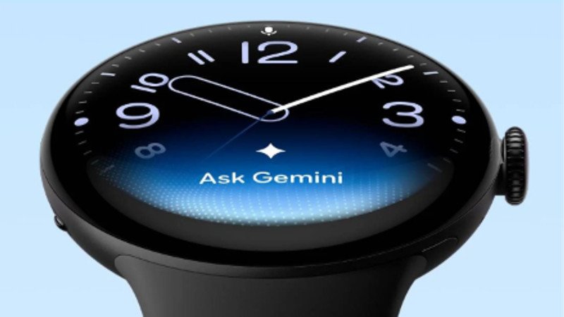 The image features a close-up of a smartwatch displaying a blue gradient background and a query for 'Ask Gemini' on its screen. The watch has a sleek design with prominent hour and minute hands.