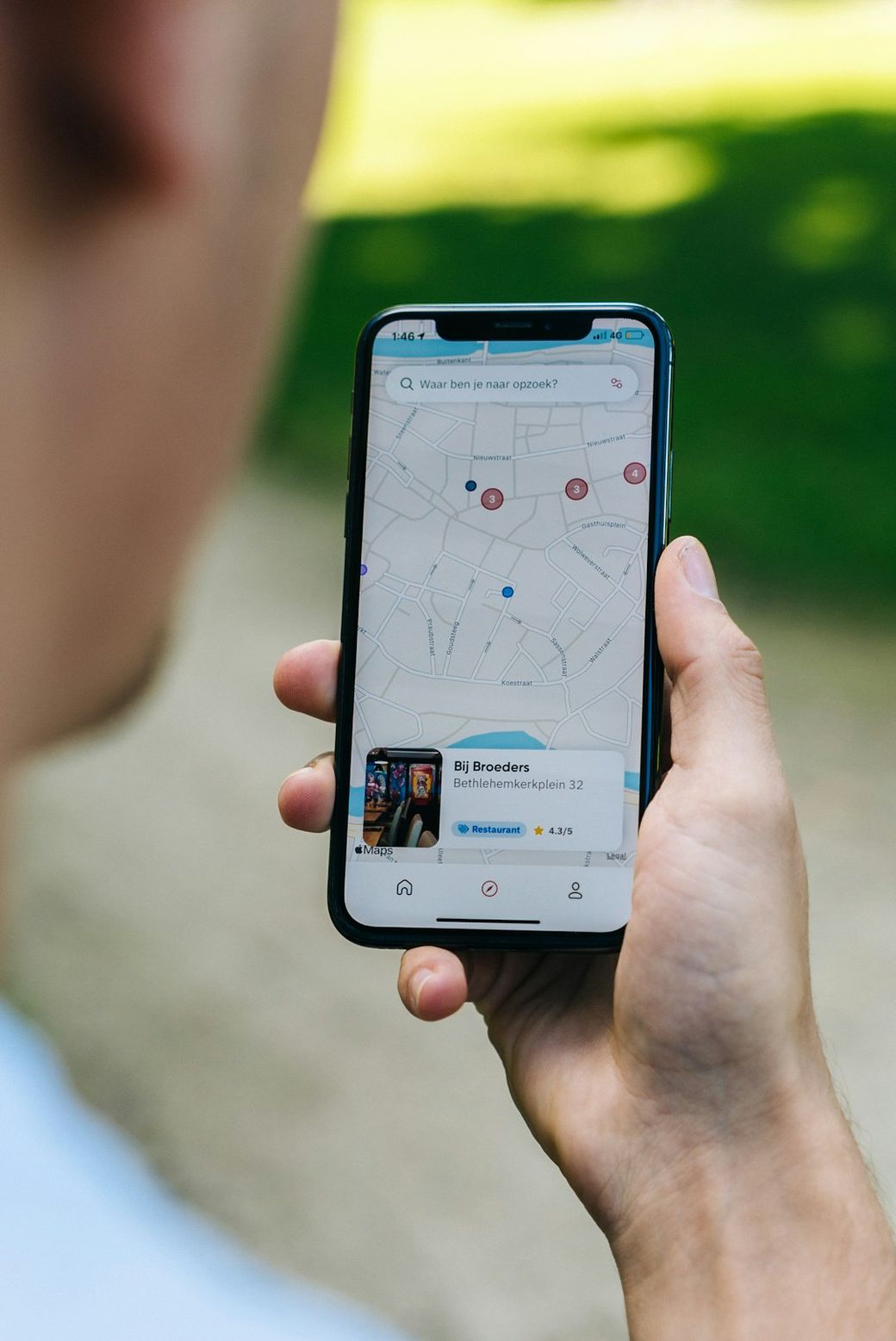A person is holding a smartphone displaying a map application with marked locations. The user's hand is positioned with the phone facing towards the viewer, indicating active use of navigation features. — Credit: Photo by CardMapr.nl on Unsplash