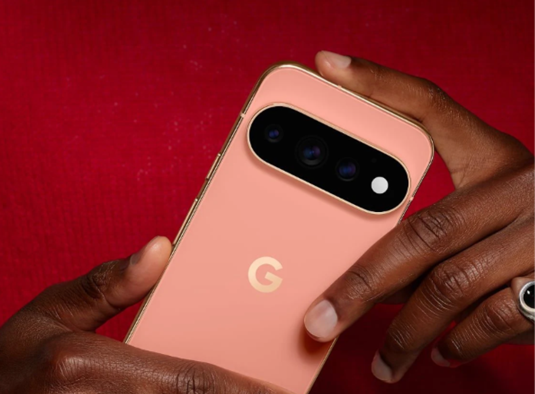 A close-up image of a person holding a peach-colored smartphone with a distinct camera design. The device features the letter 'G' prominently on the back, indicating its brand.