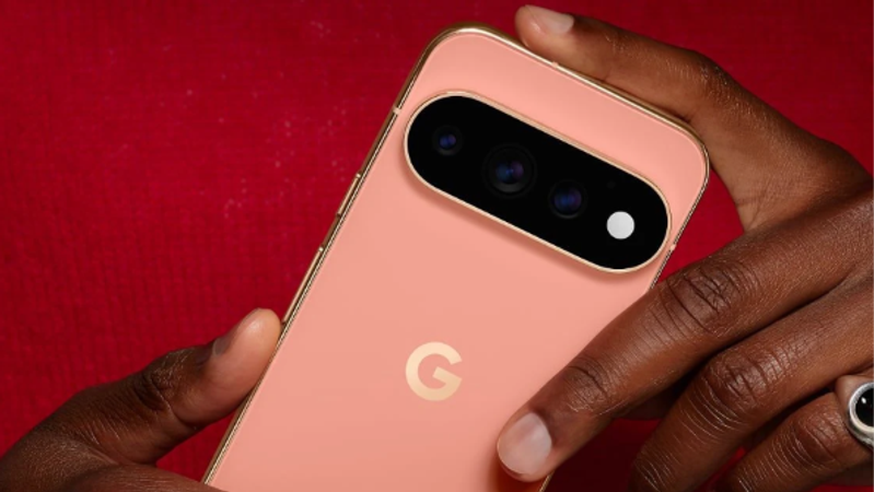 A close-up image of a person holding a peach-colored smartphone with a distinct camera design. The device features the letter 'G' prominently on the back, indicating its brand.