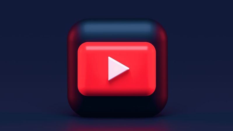 The image features a stylized YouTube play button icon set against a dark gradient background. The button is three-dimensional with rounded edges, emphasizing its visual appeal.