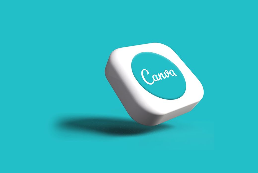 The image features a 3D representation of a logo for Canva, set against a vibrant turquoise background. The logo appears to be a round, white button with 'Canva' elegantly written in a stylized font. — Credit: Photo by Rubaitul Azad on Unsplash