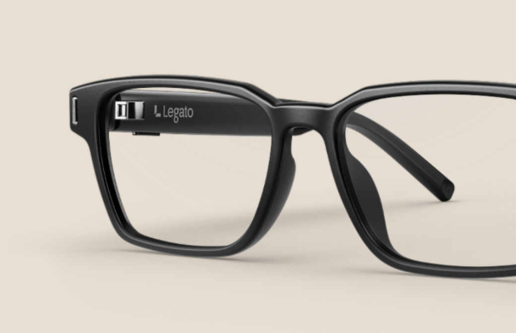 The image showcases a close-up of stylish black eyeglasses with a modern design. The frame features a logo on the inner side, emphasizing its contemporary appeal.