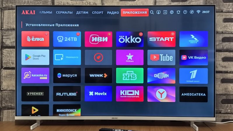 The image shows a smart TV displaying various application icons on its home screen. The interface features a grid layout of colorful app logos, indicating a selection of entertainment and media streaming options.
