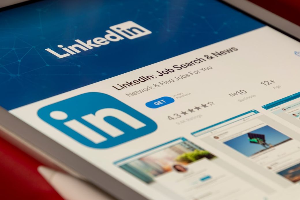 The image features a close-up of a tablet screen displaying the LinkedIn app with a focus on its Job Search and News functionalities. The interface highlights job networking services and showcases various job listings and updates. — Credit: Photo by Souvik Banerjee on Unsplash