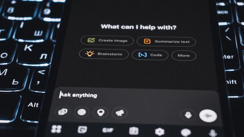 A close-up view of a smartphone interface displaying various options for assistance, such as 'Create image' and 'Summarize text'. The background features a illuminated keyboard, enhancing the tech-centric feel of the image.