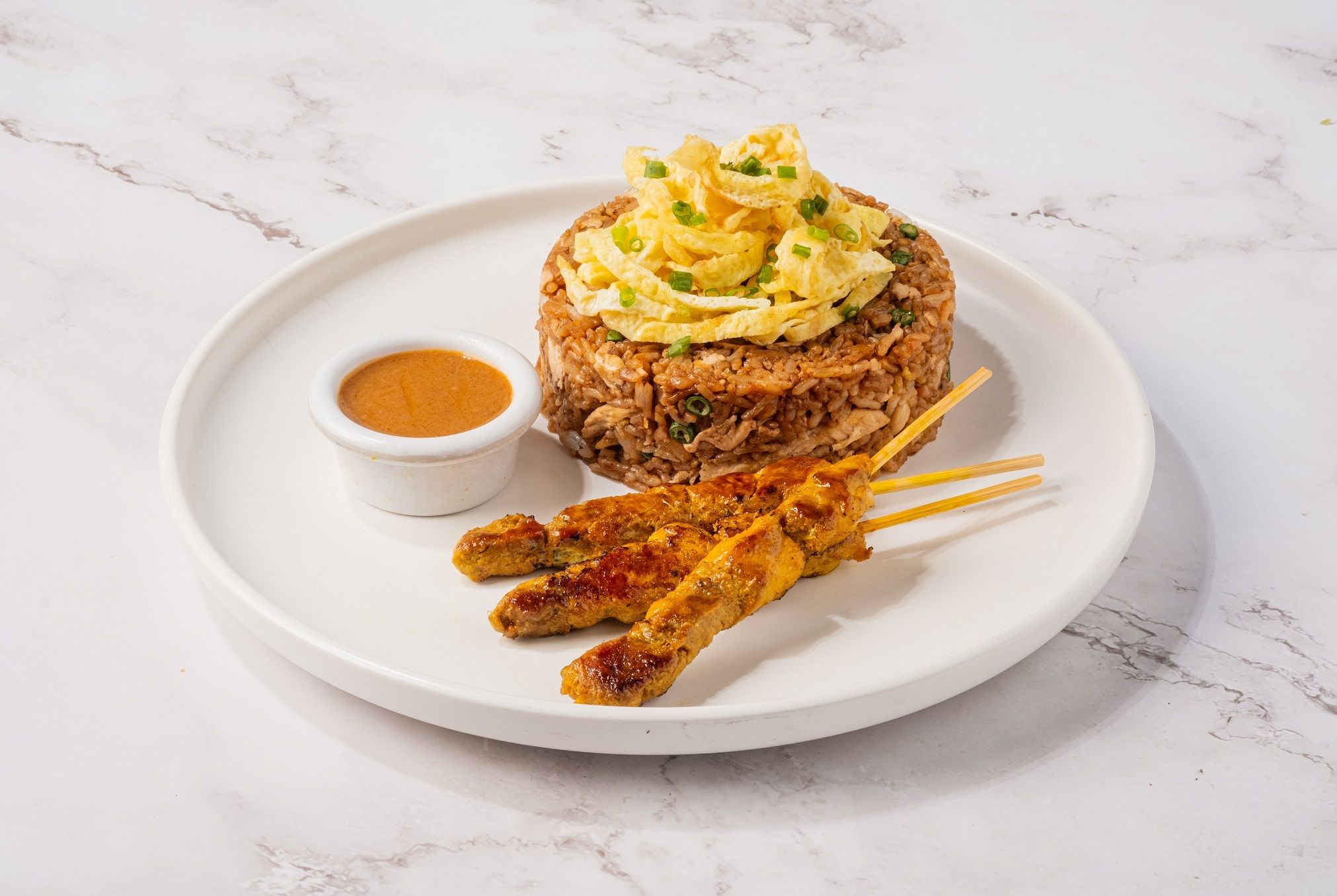 Secret Recipe’s fried rice topped with shredded omelet, served with chicken satay skewers and a cup of peanut sauce