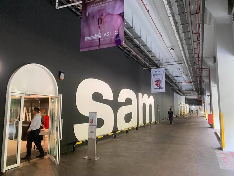 Industrial walkway at Tanjong Pagar Distripark with giant white Sam letters and an arched gallery entrance