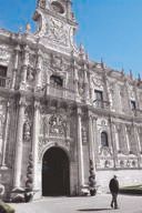 Ornate plateresque facade of the Parador de San Marcos in León, a lone figure walking past its arched entrance