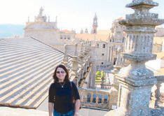 Donna Perez standing among stone pinnacles on the rooftop of the Santiago de Compostela Cathedral