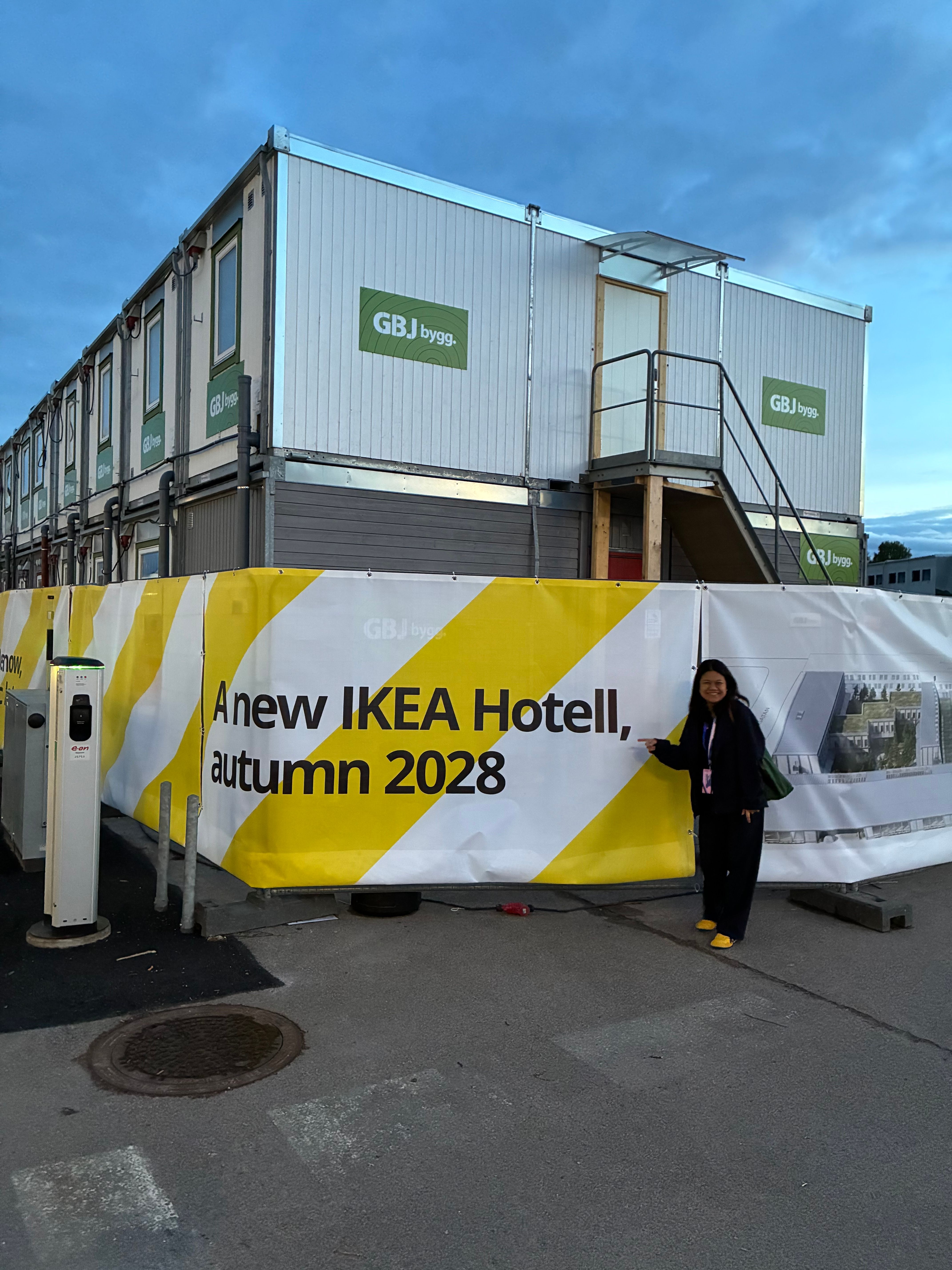 Woman points at a construction site banner announcing A new IKEA Hotell, autumn 2028 in Älmhult
