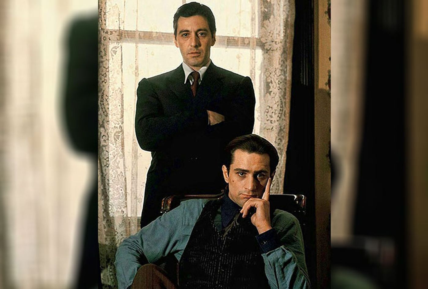 Al Pacino stands arms crossed behind a seated young Robert De Niro in a Godfather Part II publicity shot