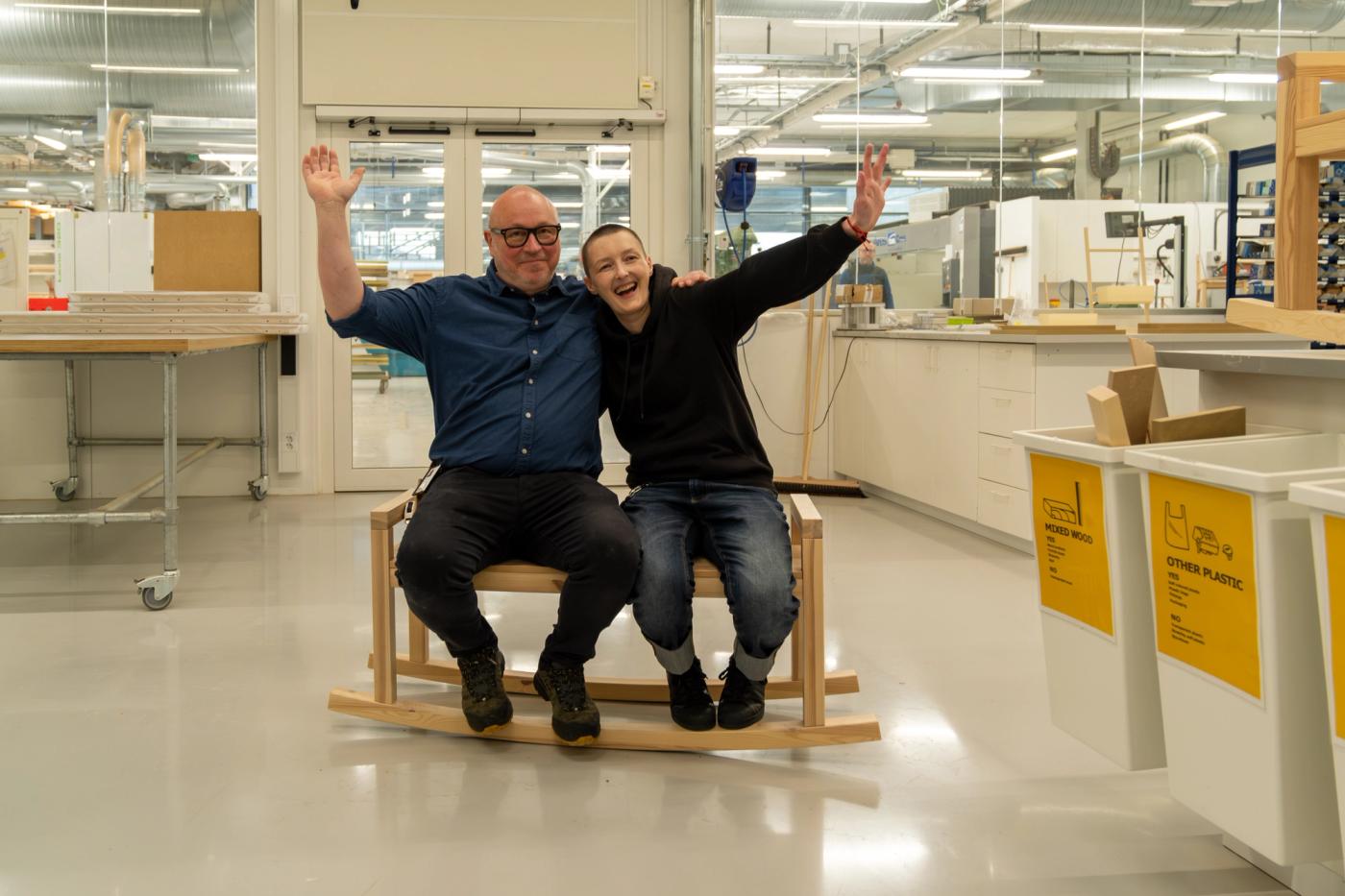 Marta Krupinska and Fredrik Larsen ride their rocking bench, arms raised, in an IKEA workshop