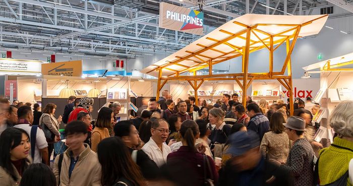 Crowds fill the Philippines stand at the Frankfurter Buchmesse, a kite-framed timber canopy and book-lined shelves under a Philippines banner in the exhibition hall