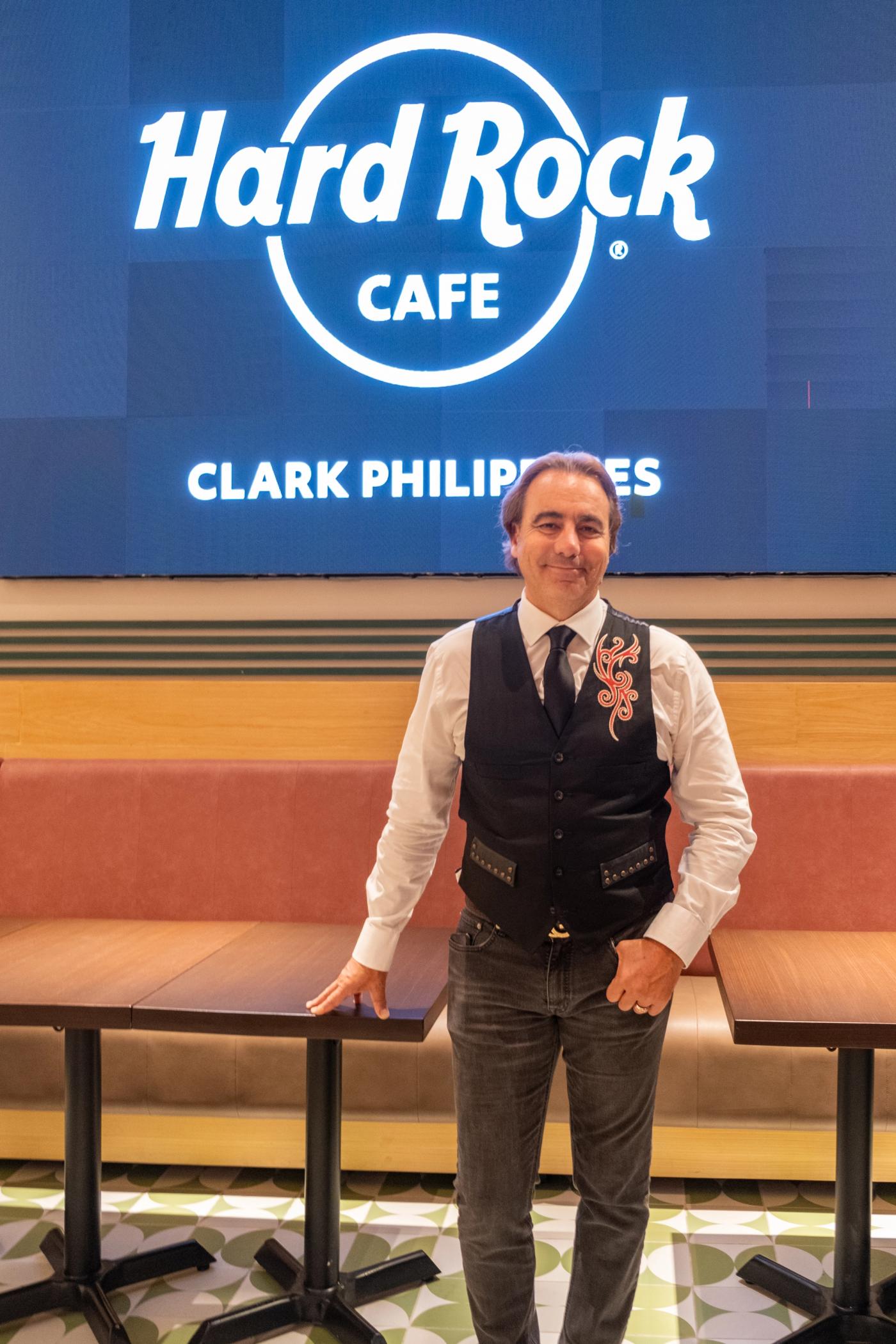 Tom Perez of Hard Rock International stands before the cafe’s glowing blue Clark Philippines sign