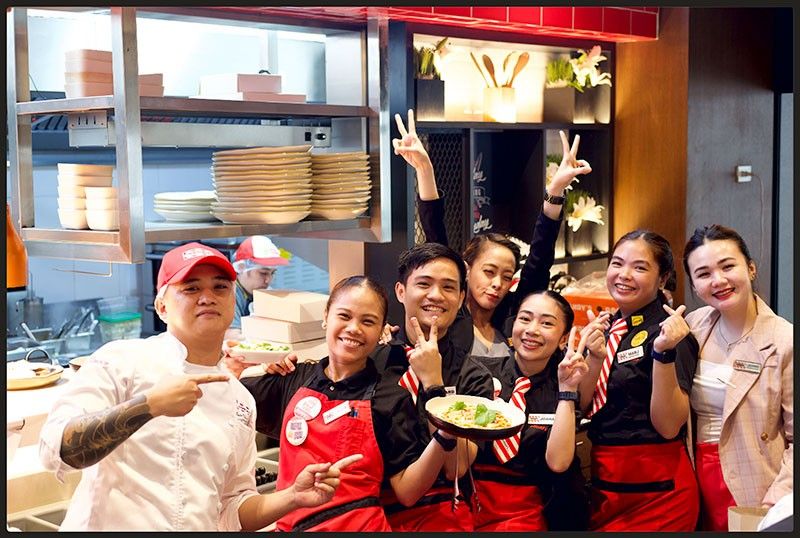 Group portrait of TGI Fridays One Ayala team members in their black uniforms posing together inside the restaurant