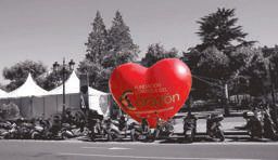 Giant red heart balloon standing out against a black and white street scene with parked scooters in La Rioja