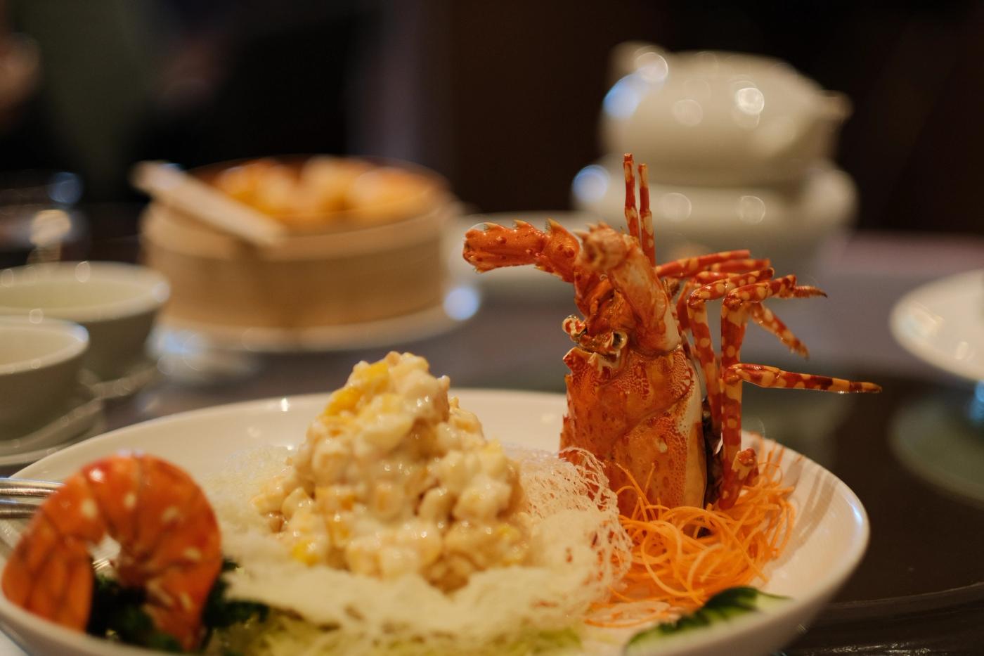 Deep-fried lobster salad served with mango salad on a white plate decorated with a whole lobster shell and head