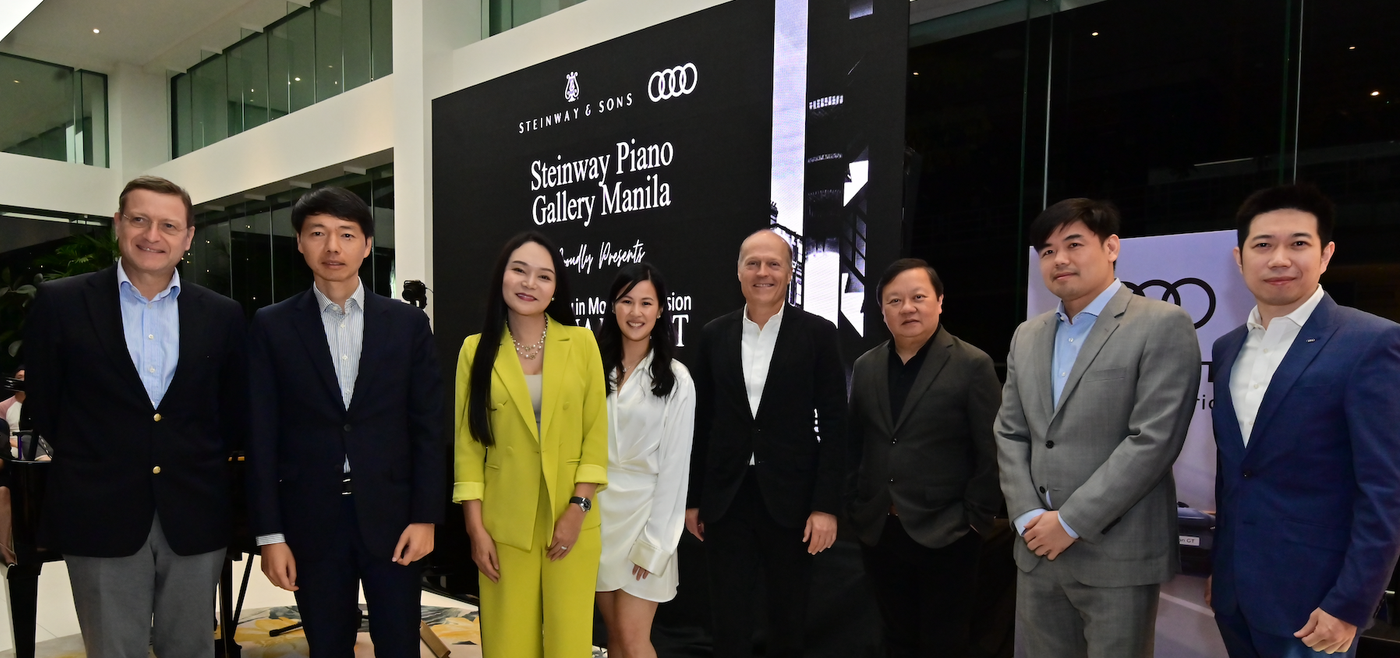 Group photo of PGA Cars, Steinway & Sons, and Lucerne executives posing with German pianist Joja Wendt in front of a red Audi car