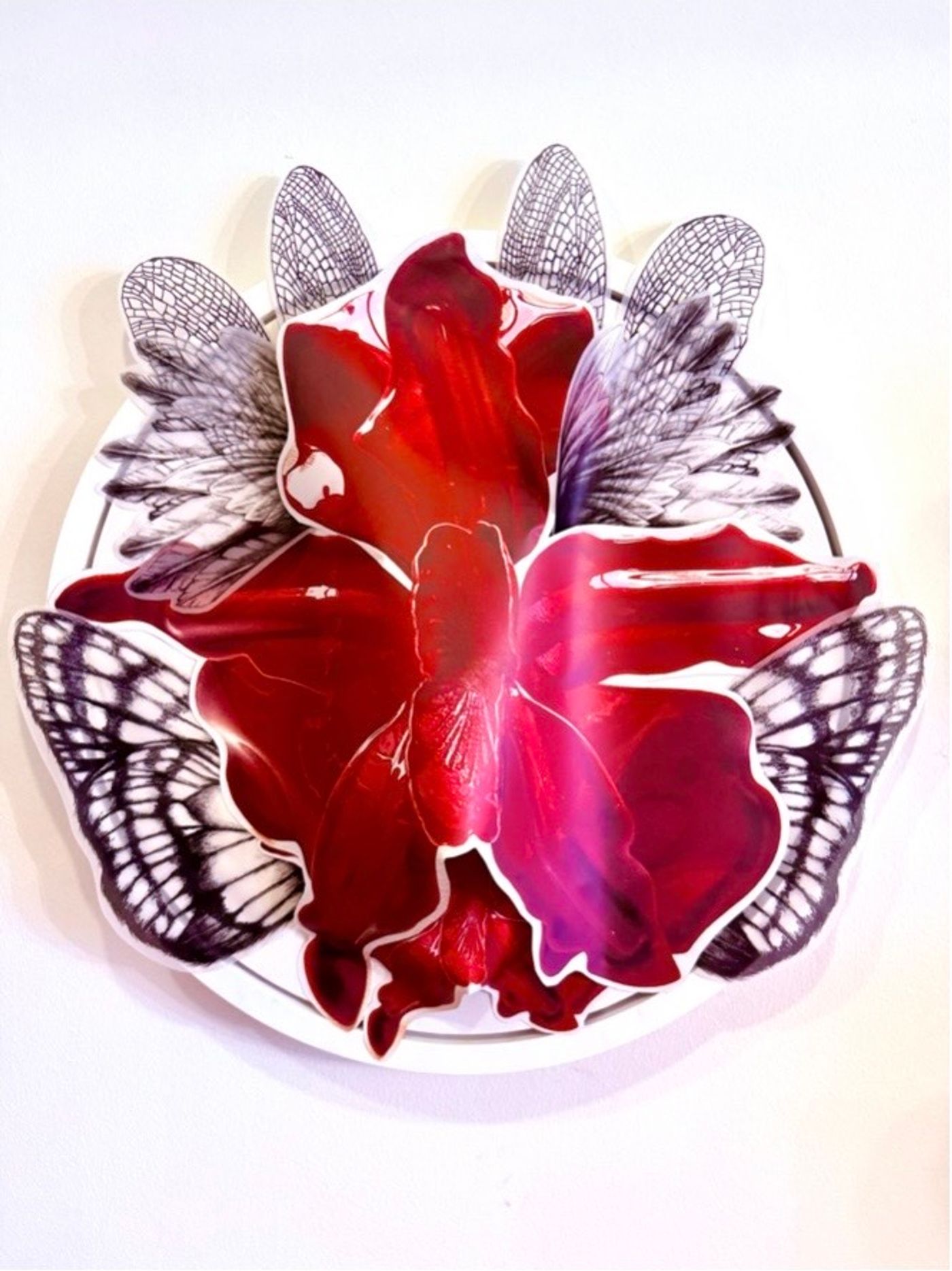 A Spell For Creation by Katya Angara, a glossy red orchid-like bloom collaged over drawn dragonfly and butterfly wings on a round white panel