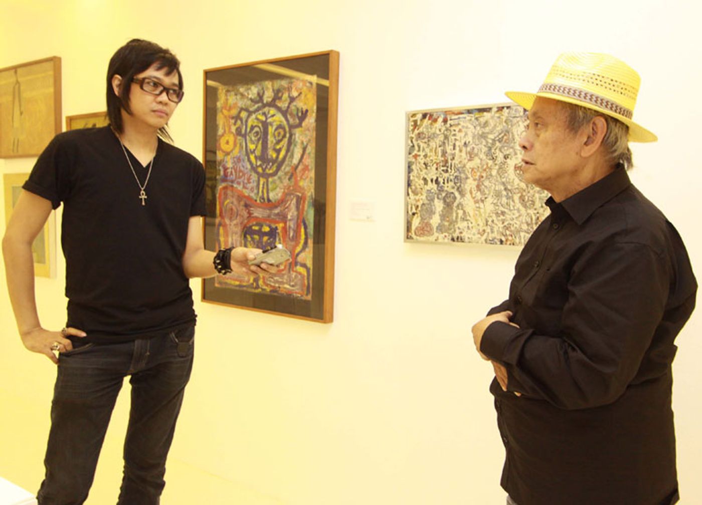 Igan D’Bayan interviewing David Medalla, in a yellow hat, before framed drawings in a Manila gallery in 2011