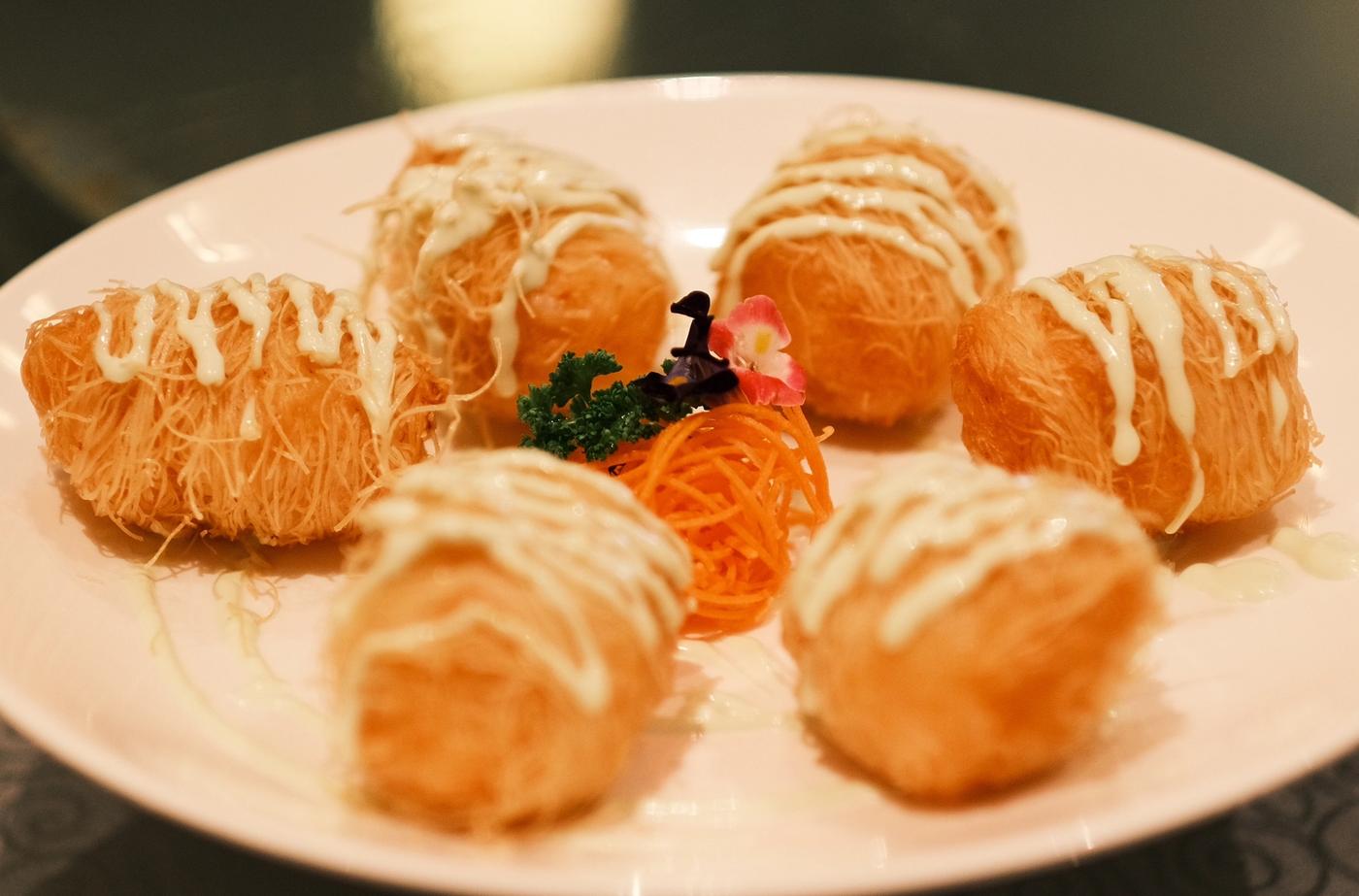 Six kataifi-wrapped fried lobster rolls drizzled with creamy sauce on a white plate at Summer Palace