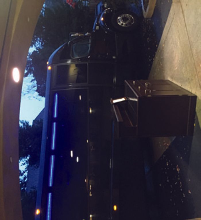 The black Netflix press bus parked at dusk, cases stacked beside its open cargo bay