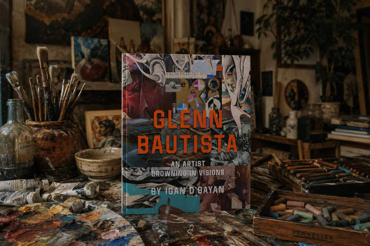 The coffee-table book Glenn Bautista: An Artist Drowning in Visions by Igan D’Bayan stands on a paint-spattered studio table among jars of brushes, oil paint tubes and a box of Sennelier pastels