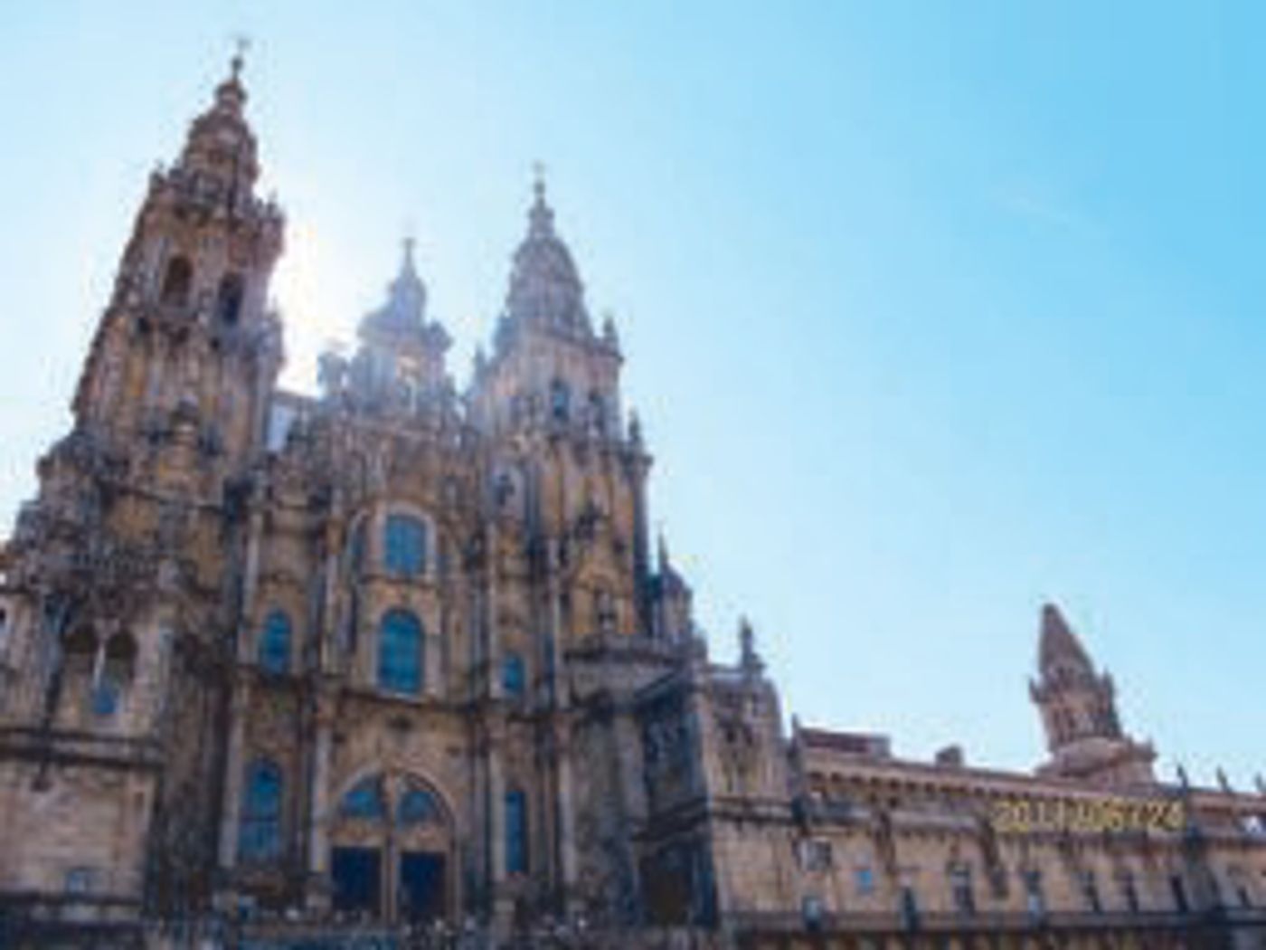 Stone towers and ornate facade of the Santiago de Compostela Cathedral against a clear blue sky