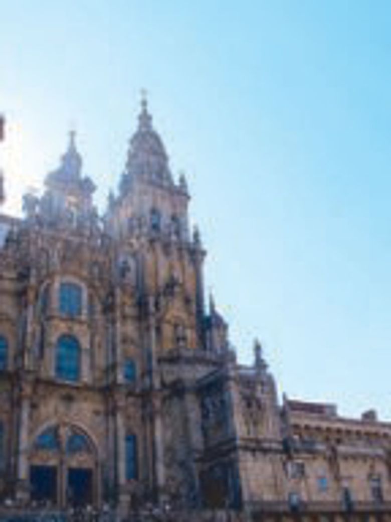 Stone towers and ornate facade of the Santiago de Compostela Cathedral against a clear blue sky