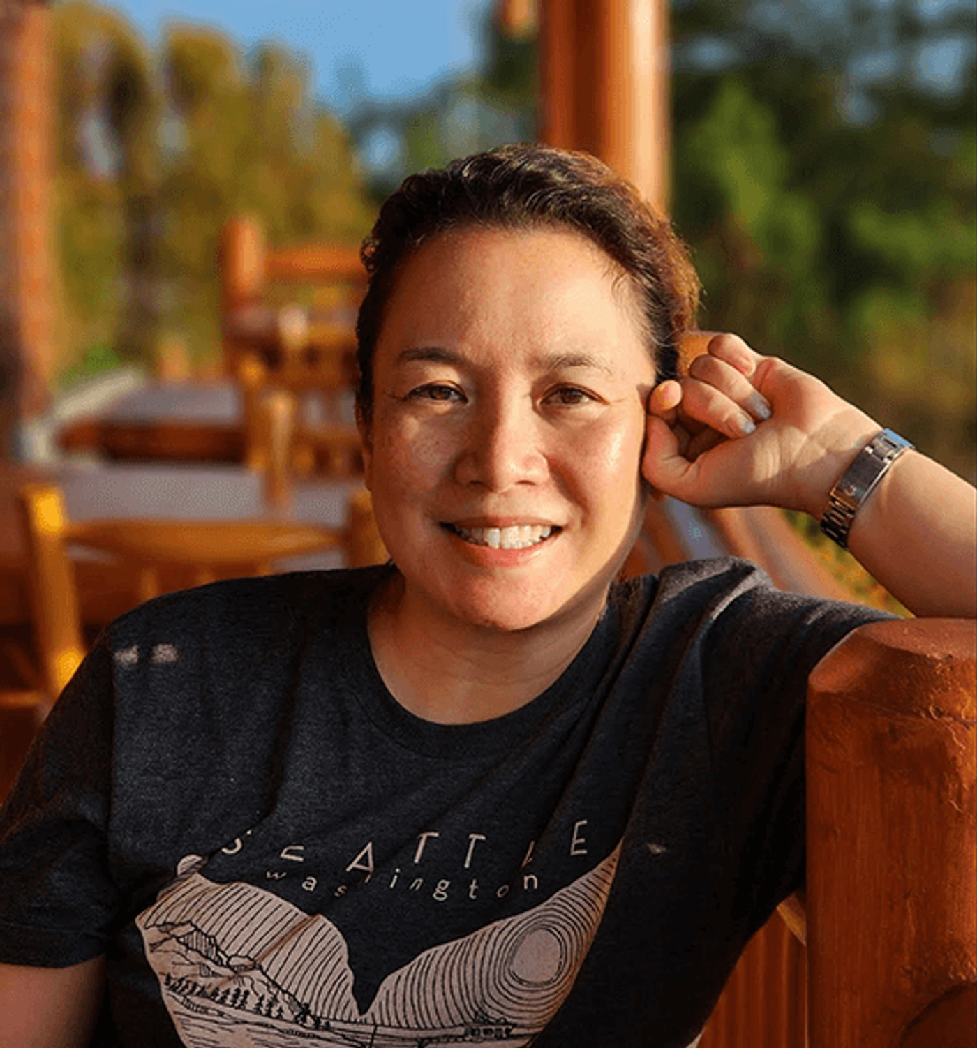 Portrait of artist Mia Herbosa smiling outdoors leaning on a wooden railing