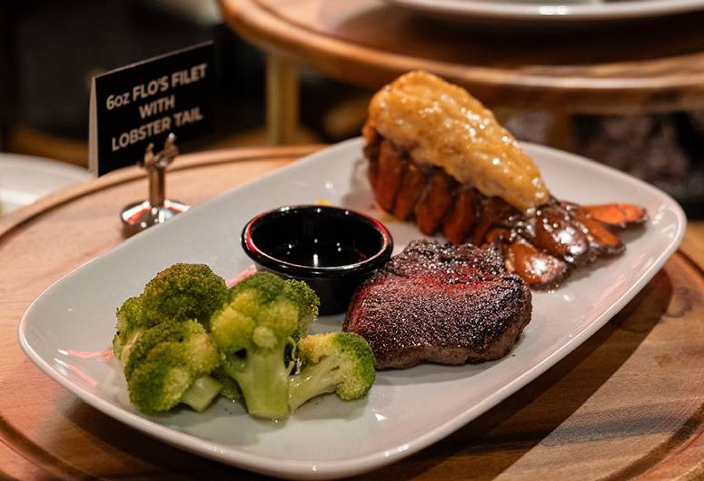 Flo’s Filet with a lobster tail, broccoli and dipping sauce arranged on a long white platter