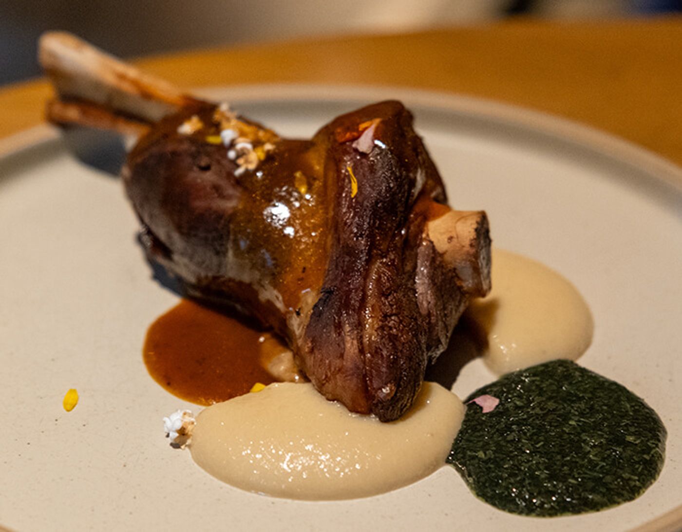 Glazed lamb shank with protruding bones over mushroom puree, brown jus and a pool of mint sauce