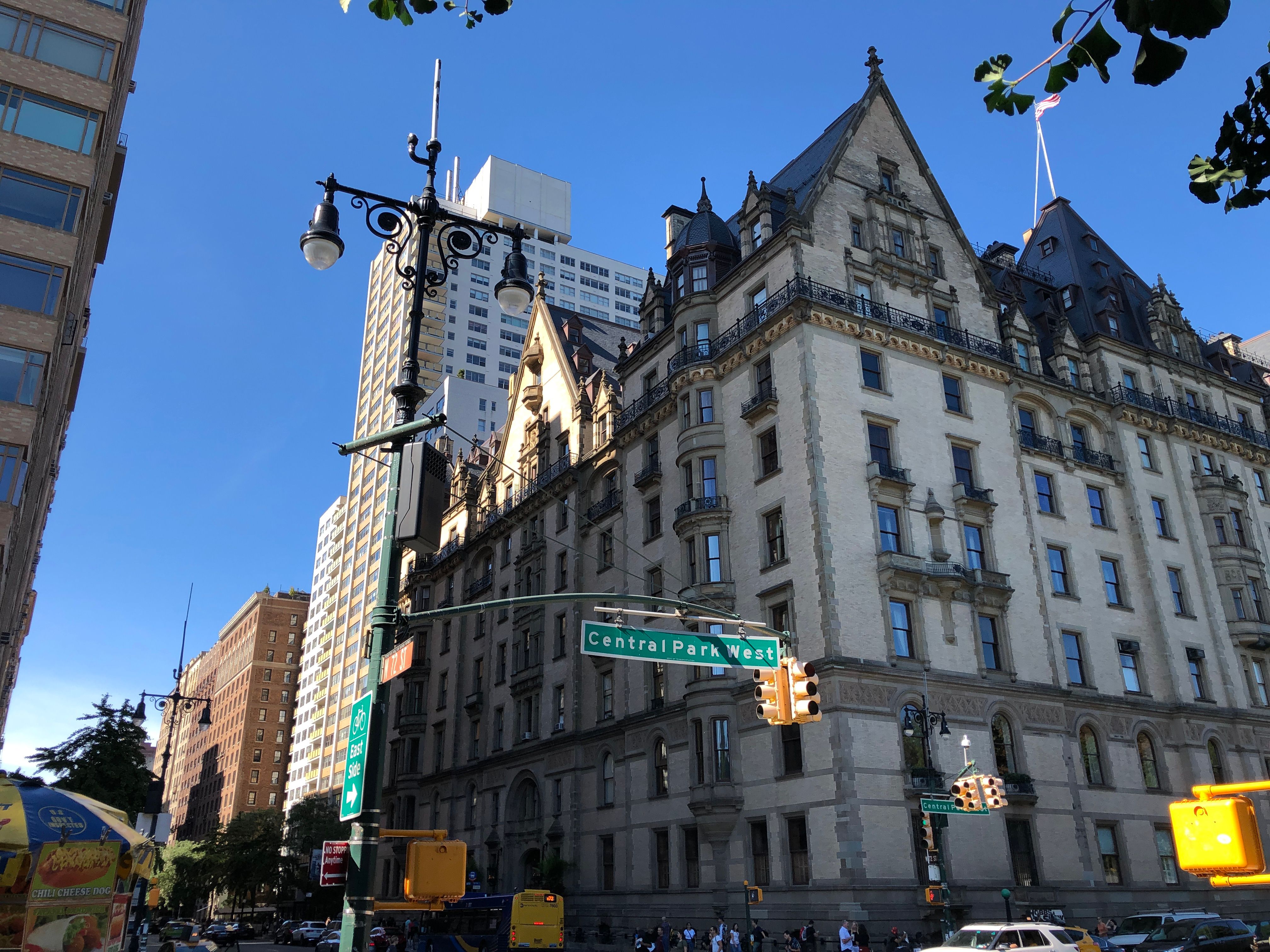 Ornate gabled apartment building on a sunlit Central Park West corner under a deep blue sky