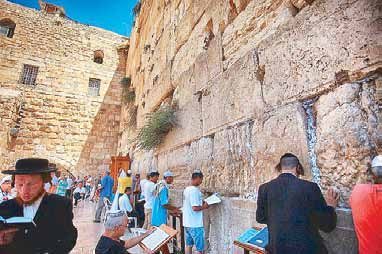 Worshippers at prayer against the towering weathered stones of the Western Wall