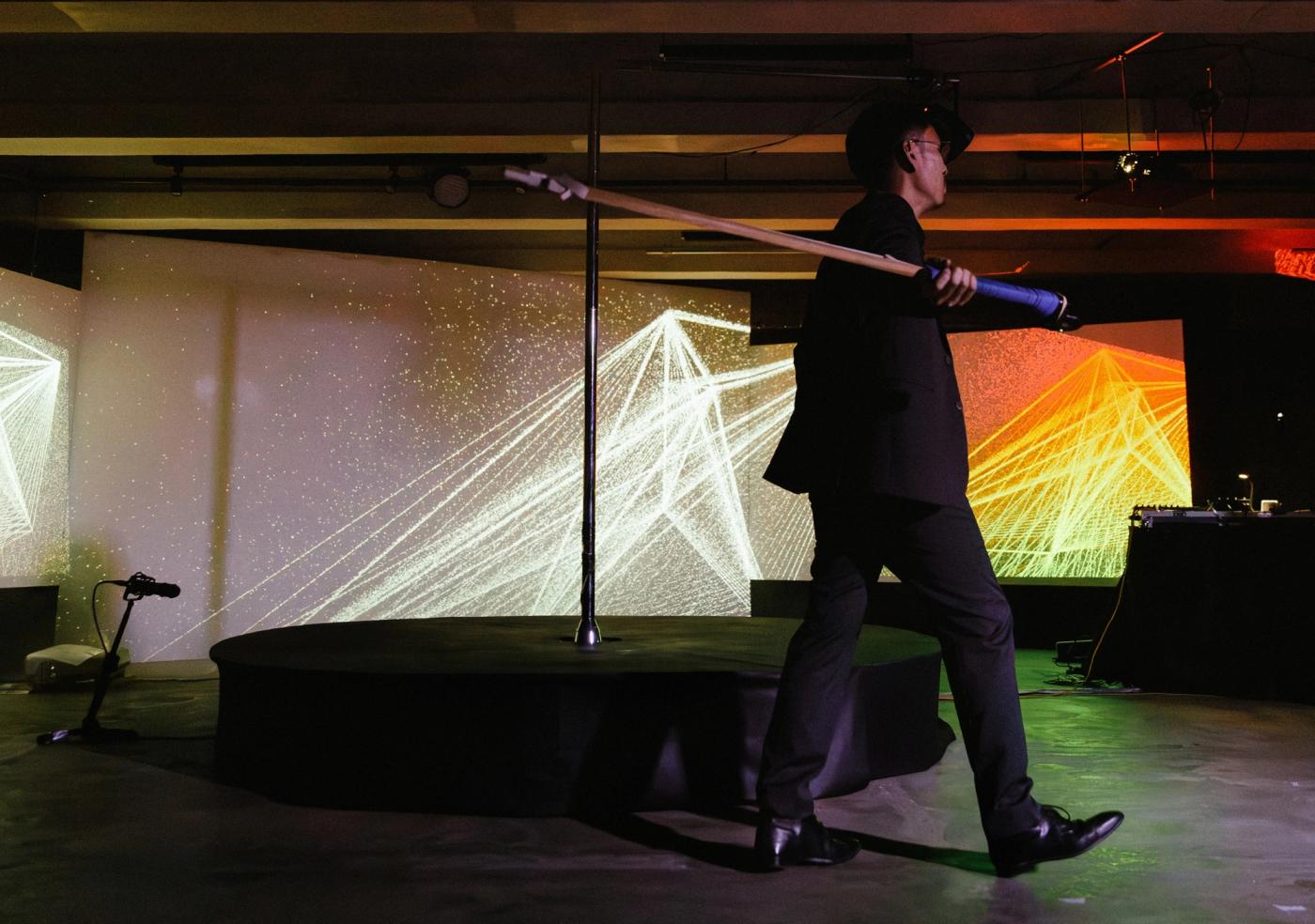 Marco Ortiga playing the Sumba wind bow instrument, holding it like a sword in front of electronics