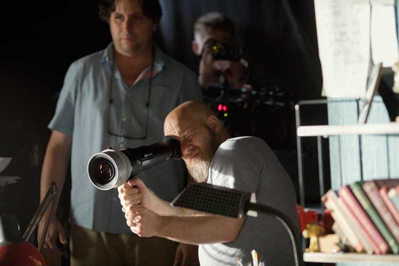 Director David Slade peers through a handheld viewfinder on the dimly lit Bandersnatch set