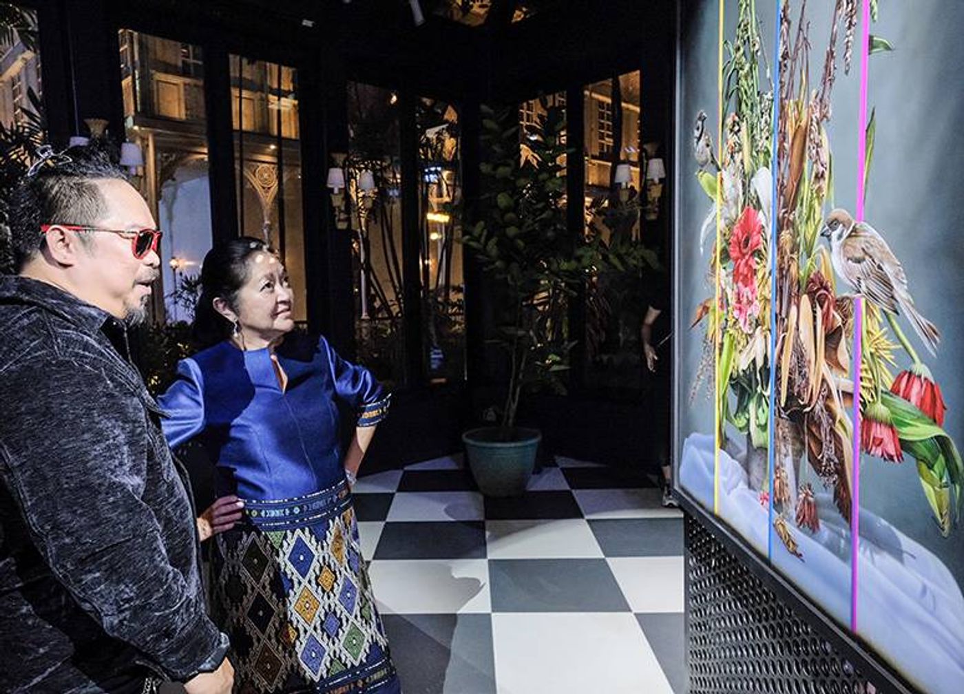 Artist Olan Ventura and First Lady Liza Araneta-Marcos standing together in front of a colorful, deconstructed floral painting at Goldenberg Mansion