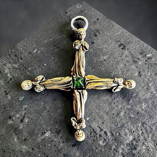 Silver cross by Michelline Syjuco assembled from wingless angel figures around a green center stone