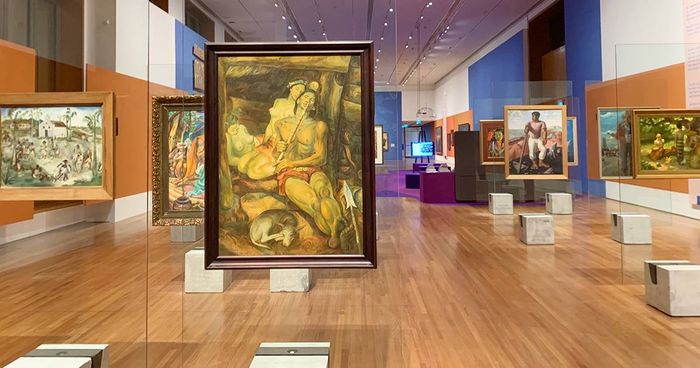 Gallery view of the Tropical exhibition, paintings hung on glass panels above a wooden floor