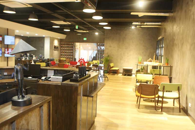 An open clinic waiting area with a long wooden counter, pale floors and clusters of mid-century chairs under warm lighting