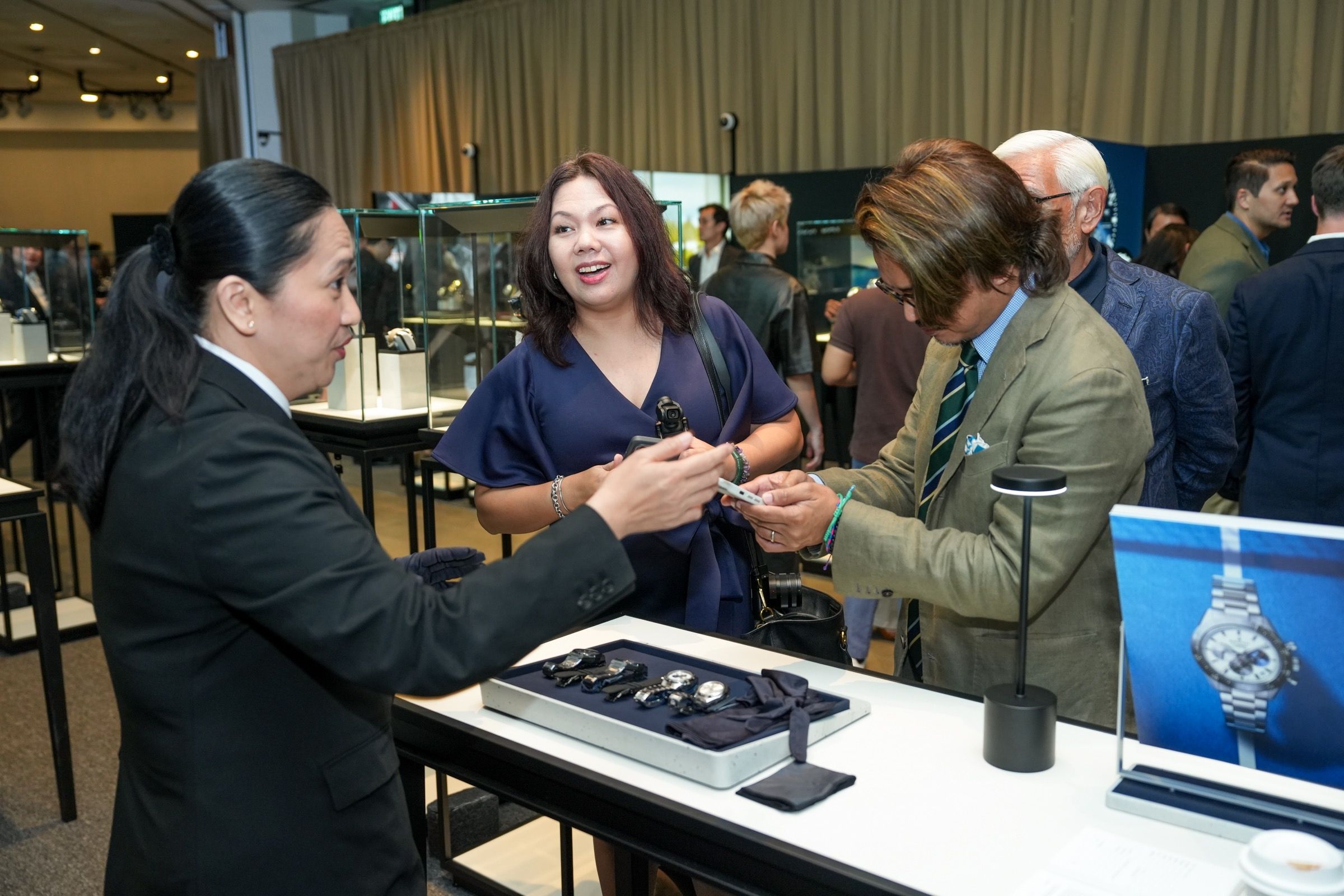 Guests in conversation with a watch specialist examining timepieces on display trays at Lucerne Watch Week