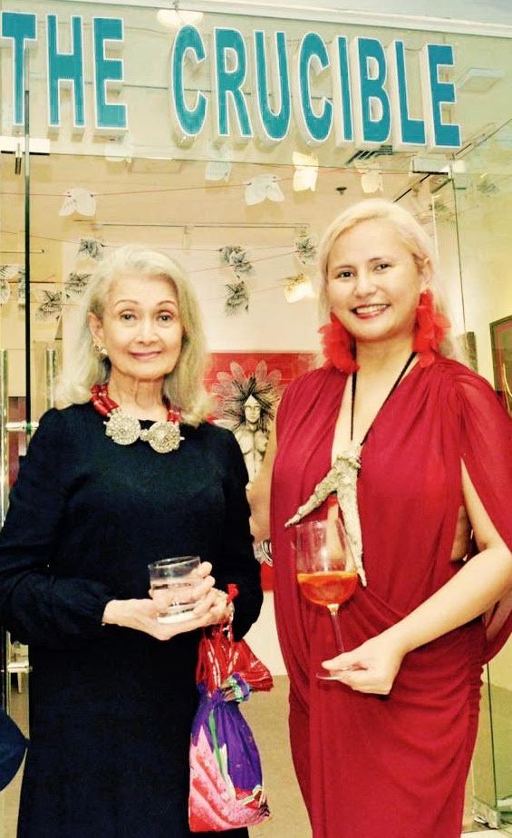 Katya Angara in a red dress with her mother Gloria Angara beneath The Crucible gallery sign at the Sorceress opening