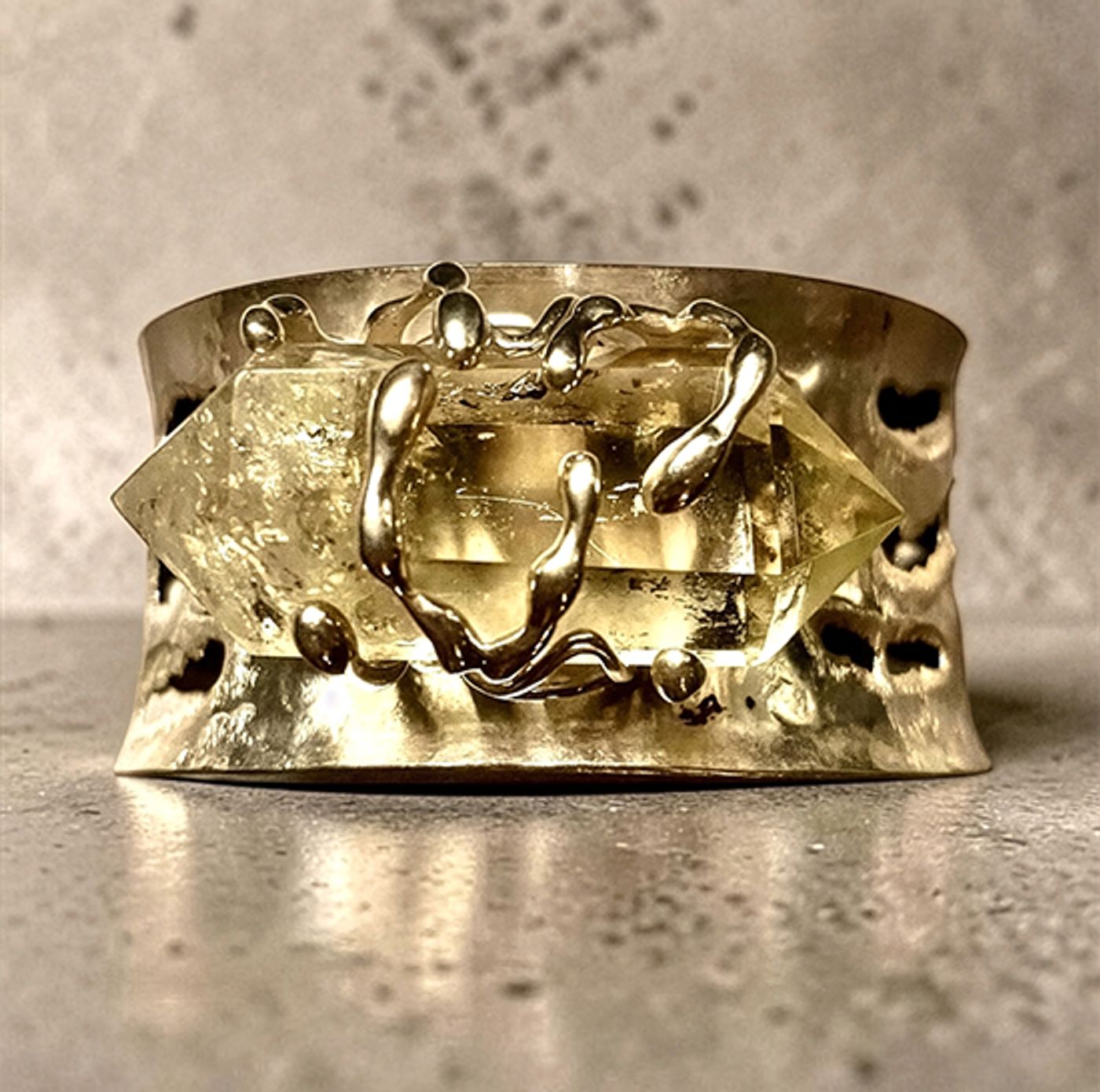 Hammered gold-toned cuff by Michelline Syjuco with sculpted tendrils gripping a double-terminated citrine crystal